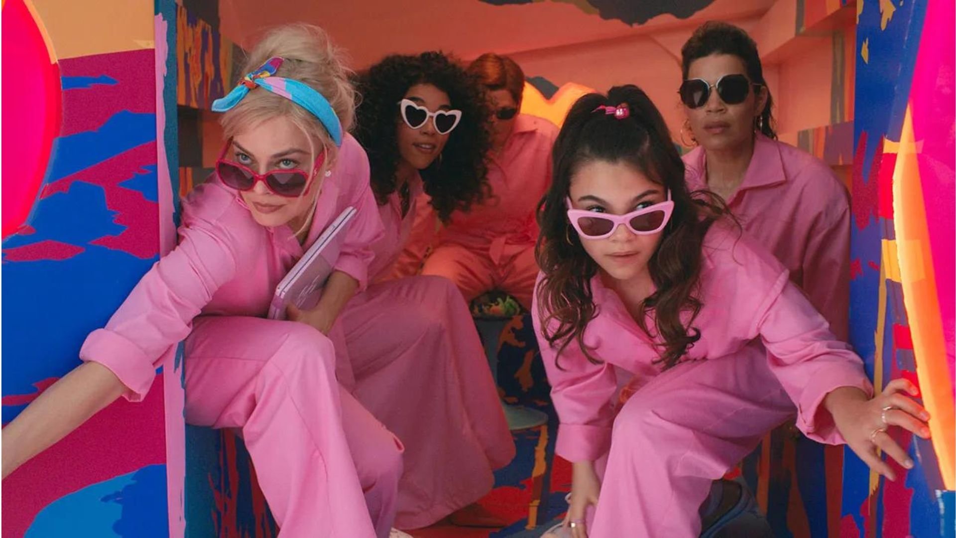 A group of Barbie in pink jumpsuits stepping out of a van in 'Barbie'