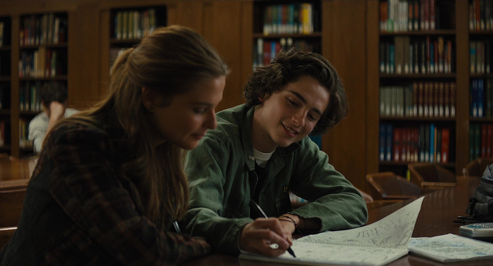 Nic (Timothée Chalamet) writing in a girl's journal in a library in 'Beautiful Boy'