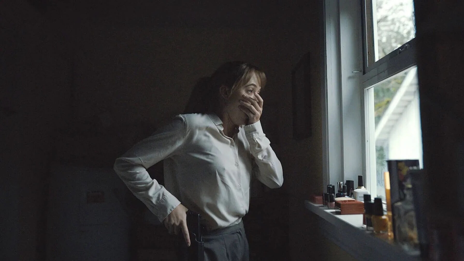 Lee Harker (Maika Monroe) in shock as she stands at a window in 'Longlegs,' How ‘Longlegs’ Terrifying Marketing Teaches You to Craft the Perfect Villain