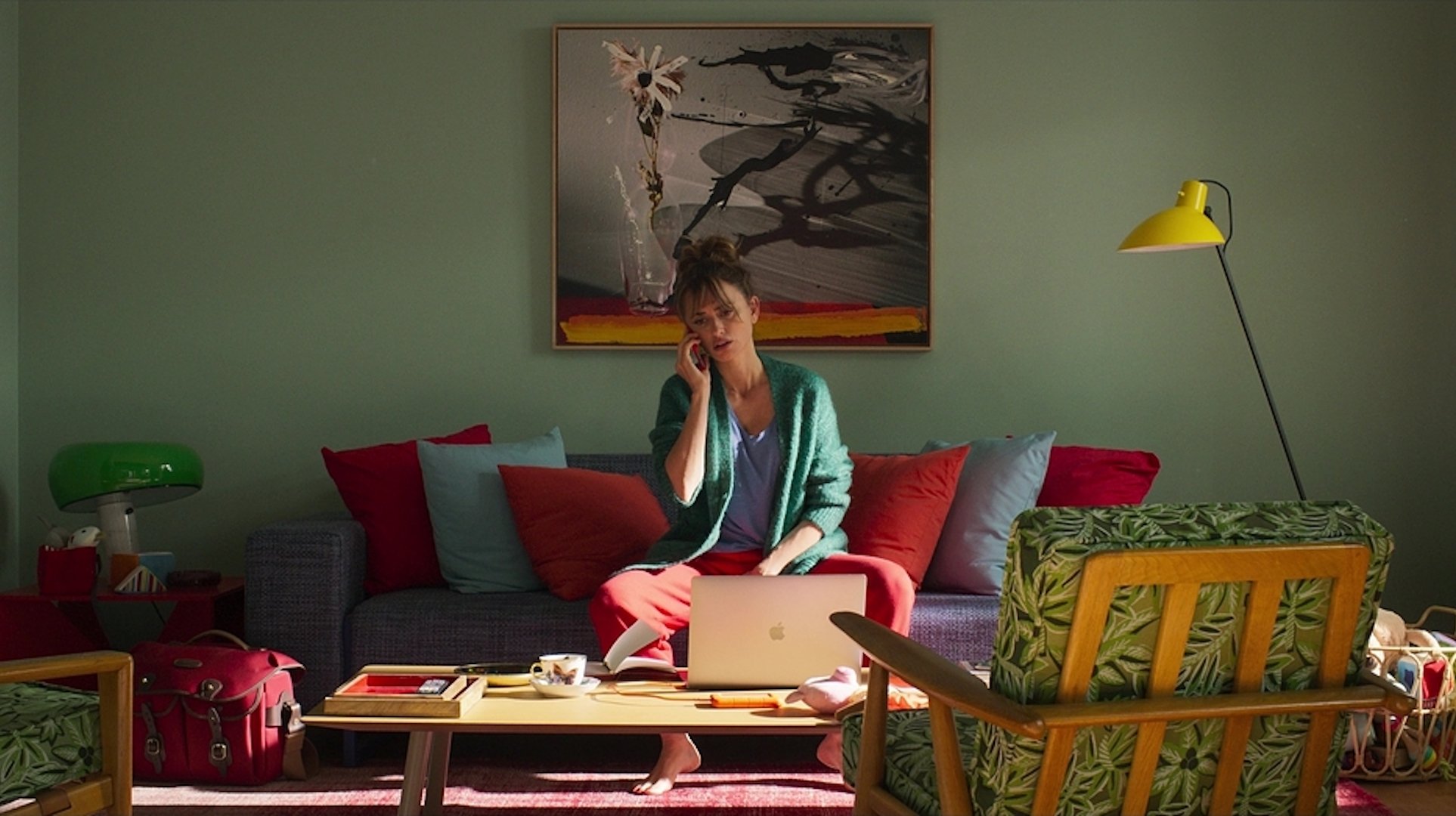 A woman talking on the phone sitting in front of a laptop in 'Parallel Mothers' (2021)