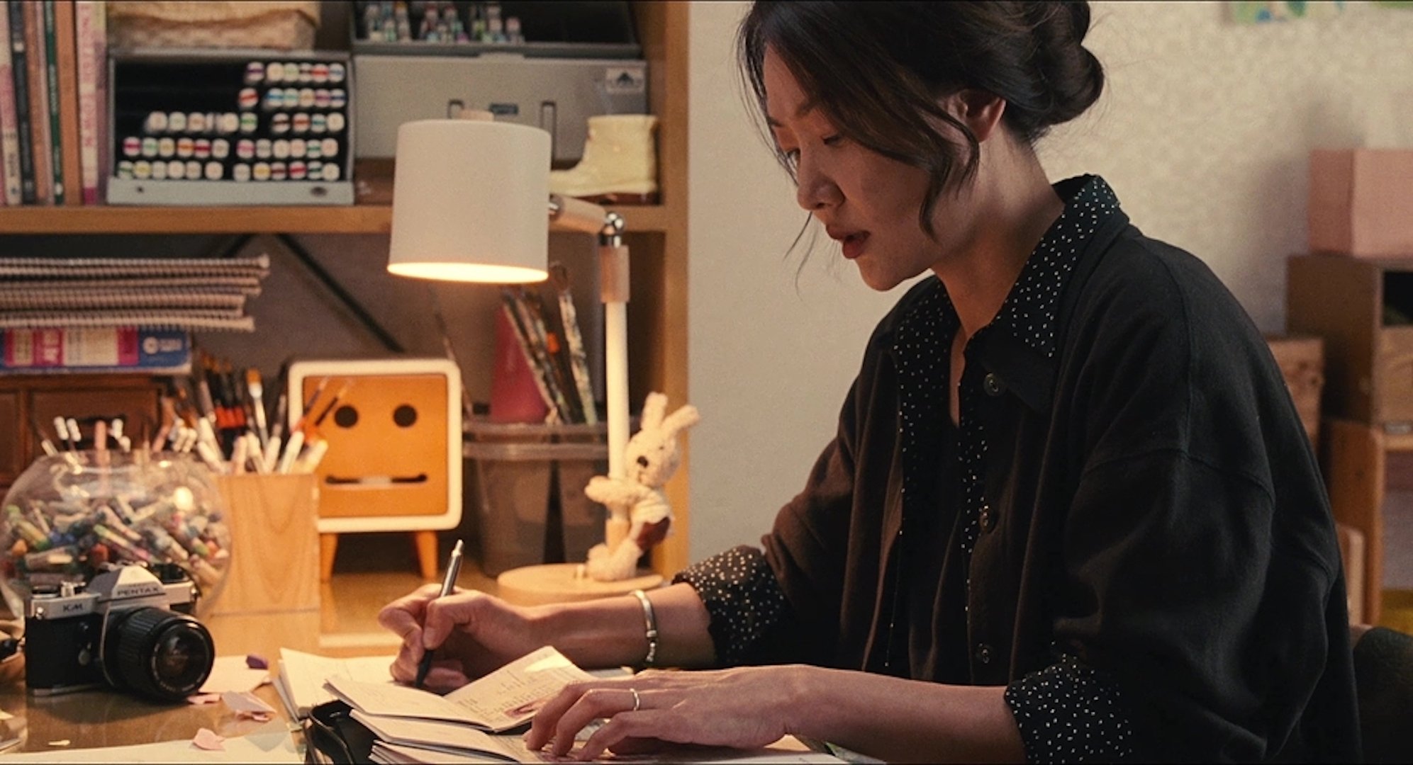 A woman writing into a notebook in 'Past Lives'