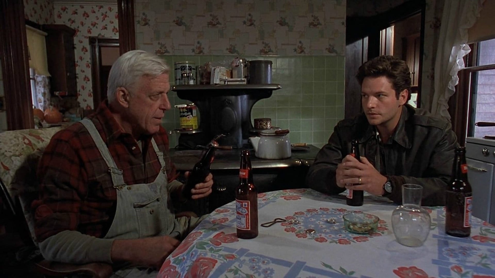 Jud (Fred Gwynne) and Louis (Dale Midkiff) drinking beer and talking at a dinner table in 'Pet Sematary;' How To Create the Suspension of Disbelief in Your Screenplay