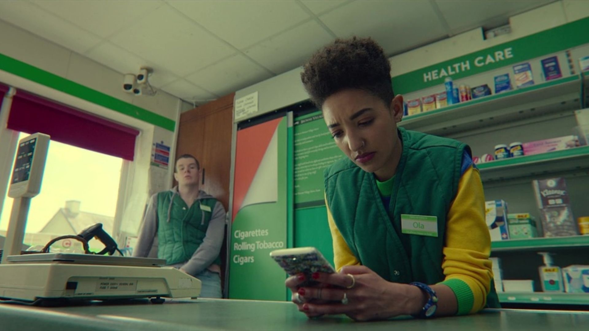 Ola (Patricia Allison) texting on her phone while working at the convenience store in 'Sex Education,' Adapting to Online Trends: Writing Content for TikTok and Shorts