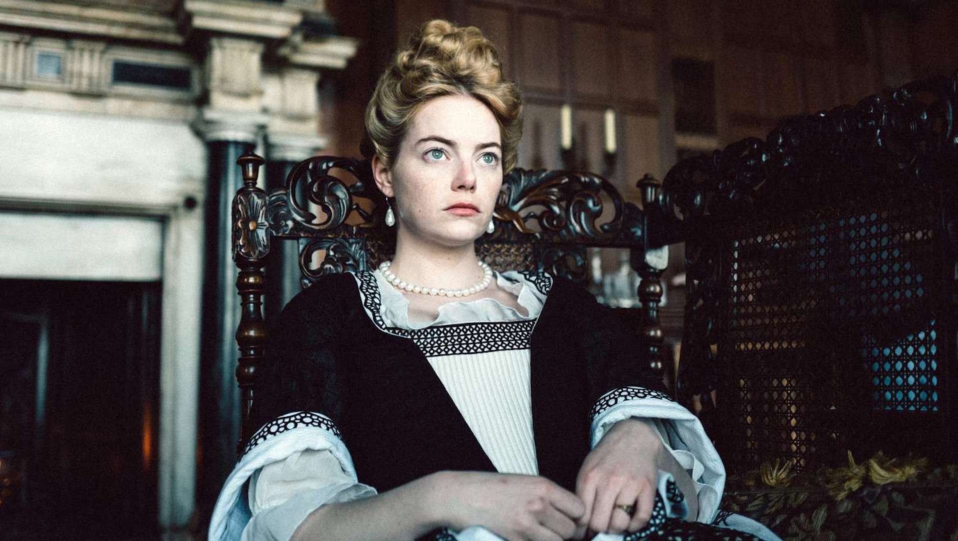 Abigail Hill (Emma Stone) sitting in a char in 'The Favourite,' 5 Ways To Write a Modern Biopic 