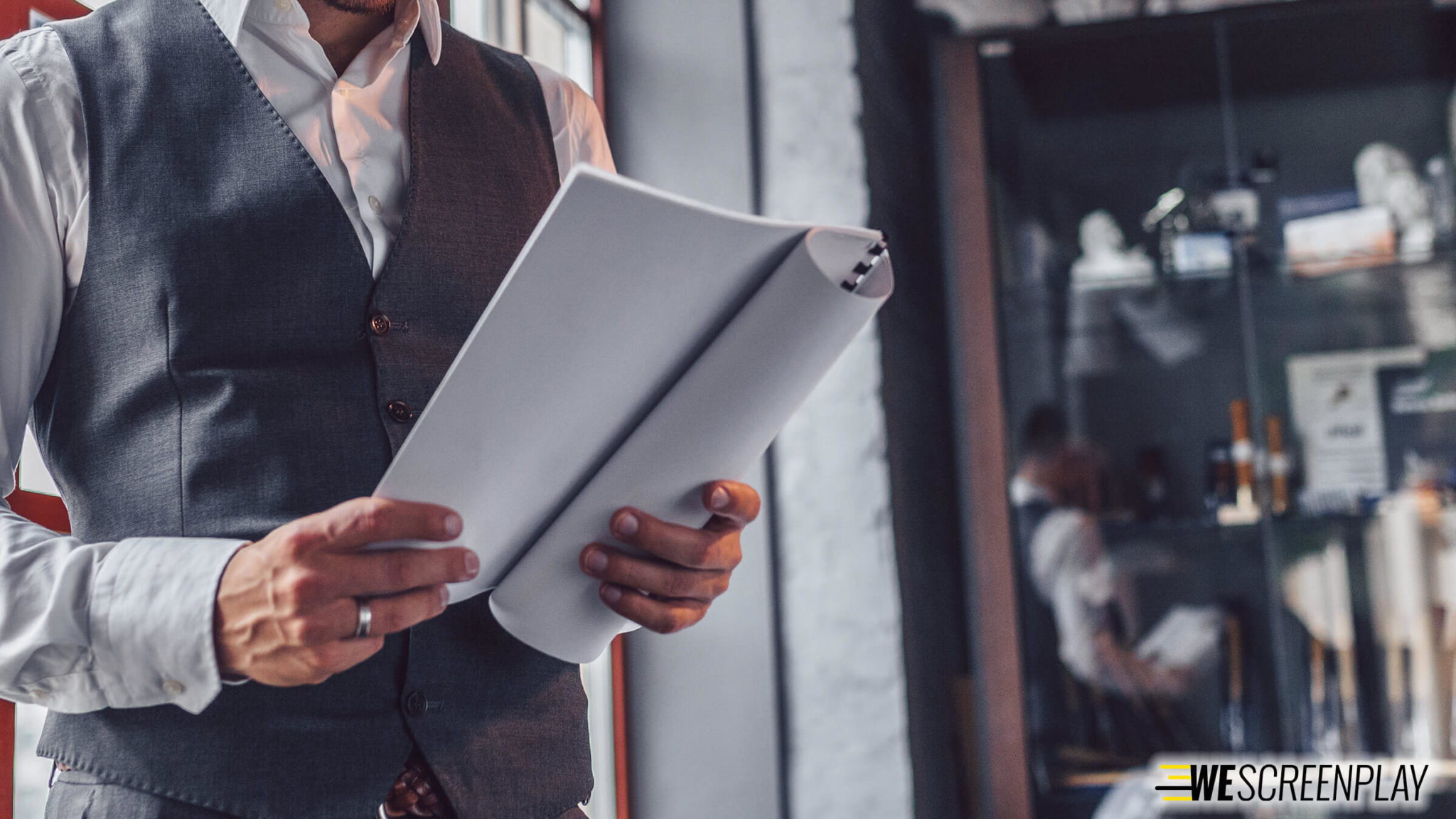 A man in a suit reading a script; 5 Screenwriting Insights from a Professional Script Reader