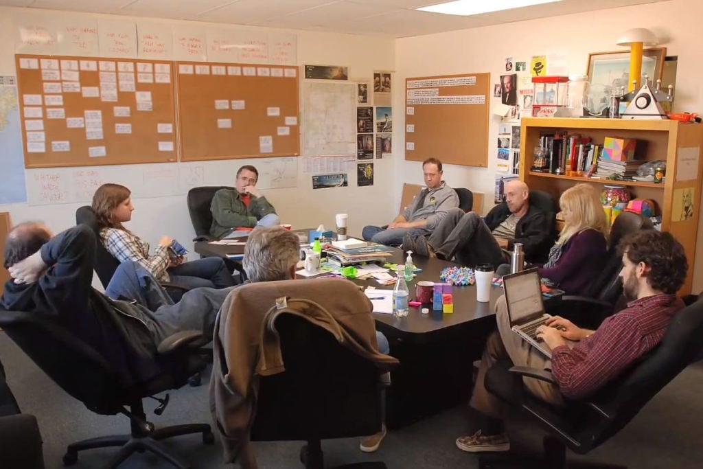 A group of writers talking and typing on their computers in a writers' room
