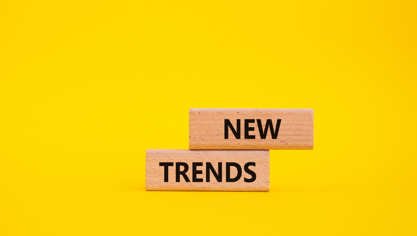 Two wooden building blocks with 'New Trends' written across them in front of a yellow background.